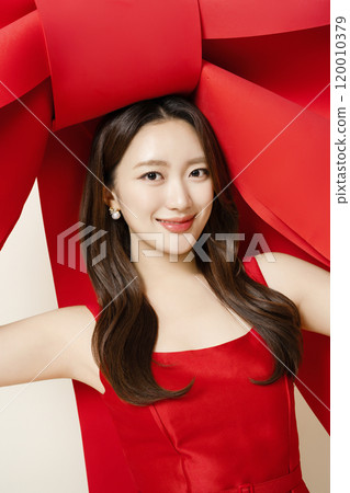 A woman in her 20s posing while holding a large ribbon 120010379