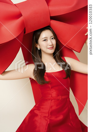 A woman in her 20s posing while holding a large ribbon A woman in her 20s posing while holding a large ribbon 120010383