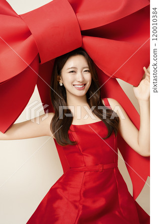 A woman in her 20s posing while holding a large ribbon 120010384