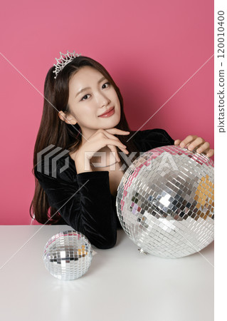 A woman in her 20s posing in front of a mirror ball 120010400