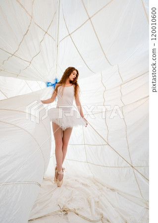 Young Ballerina Posing in White Tulle Skirt Inside a Large White Canopy 120010600