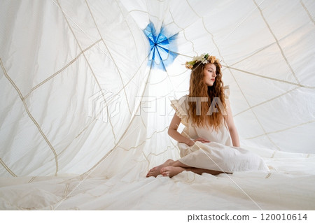 Woman in White Dress Sitting Inside Large White Canopy With Flower Crown 120010614