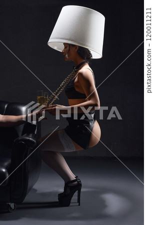 Submissive woman in black underwear on high heels with lamp serving champagne 120011211