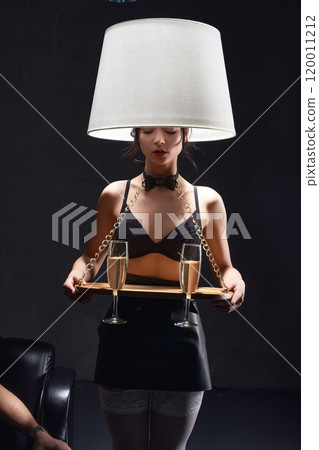 Unrecognizable woman in black underwear with lamp serving champagne in dark room Unrecognizable woman in black underwear with lamp serving champagne in dark room 120011212