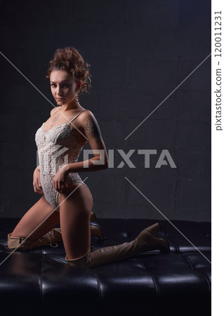 Sensual lady in provocative outfit sitting on leather couch in studio Sensual lady in provocative outfit sitting on leather couch in studio 120011231