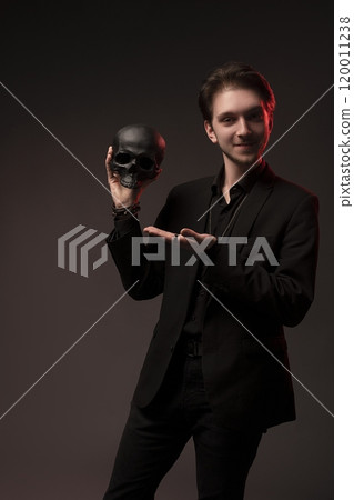 Man in black suit smile with skull in hands look at camera Man in black suit smile with skull in hands look at camera 120011238