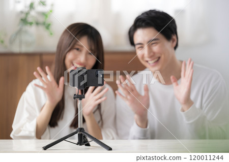 Image of a man and woman streaming videos as a couple, waving hello 120011244