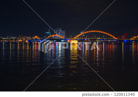 Panorama of Dragon Bridge or Cau Rong Bridge over Han River in Da Nang in Vietnam at night with a golden backlight Panorama of Dragon Bridge or Cau Rong Bridge over Han River in Da Nang in Vietnam at night with a golden backlight 120011340