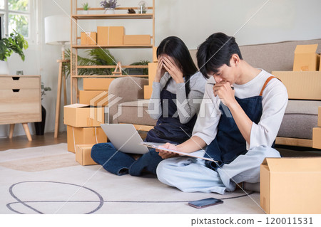 Stressed Couple Managing Online Business Facing Issues with Wrong Order Amidst Packaging Boxes at Home 120011531