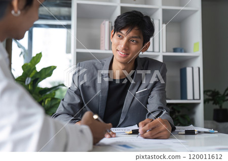 Businessman Signing Contract Agreement in Modern Office Setting with Colleague Businessman Signing Contract Agreement in Modern Office Setting with Colleague 120011612