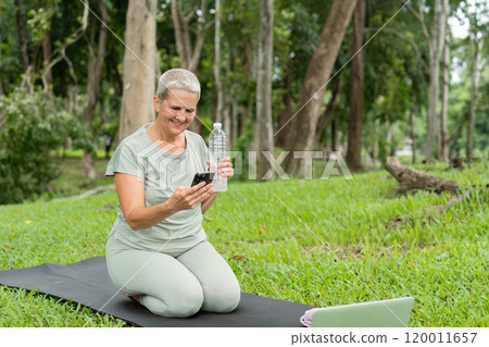 Elderly Woman Practicing Yoga in the Garden with Water Bottle and Smartphone, Outdoor Wellness and Fitness 120011657