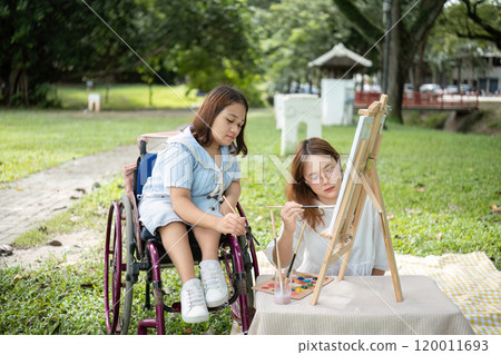 Close Friends, Disabled Young Women Drawing Together Outdoors in a Park on a Sunny Day, Embracing Creativity and Friendship 120011693