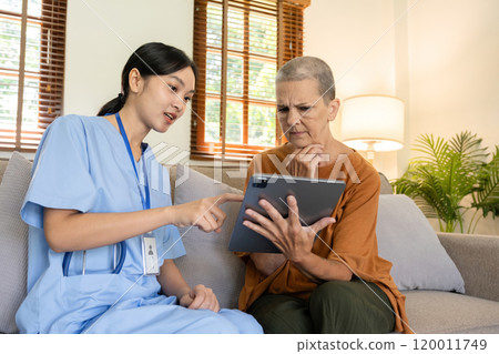 Caregiver Assisting Elderly Woman with Health Management Using Digital Tablet at Home 120011749
