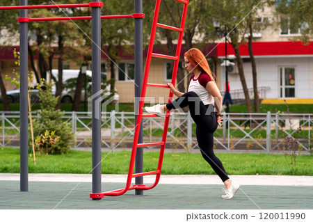 Woman lifting leg on outdoor ladder during workout 120011990