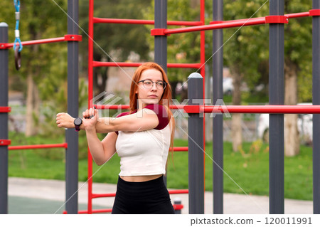Woman performing arm stretches as part warm-up routine Woman performing arm stretches as part warm-up routine 120011991