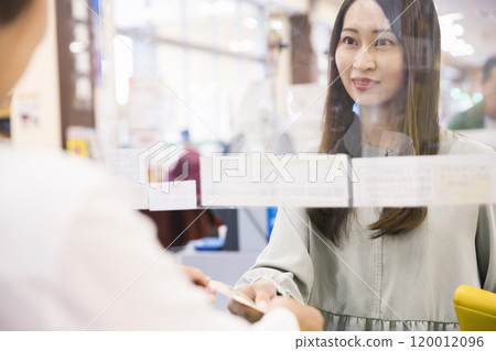 A woman handing over cash at a supermarket cash register A woman handing over cash at a supermarket cash register 120012096