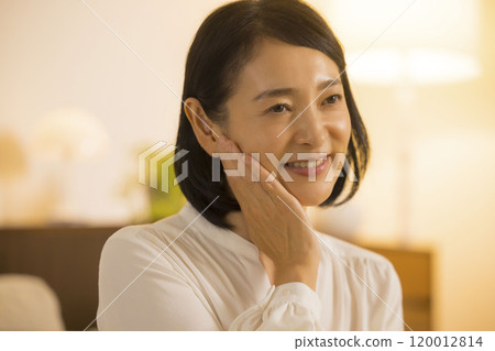 A middle-aged woman doing her skin care at night 120012814