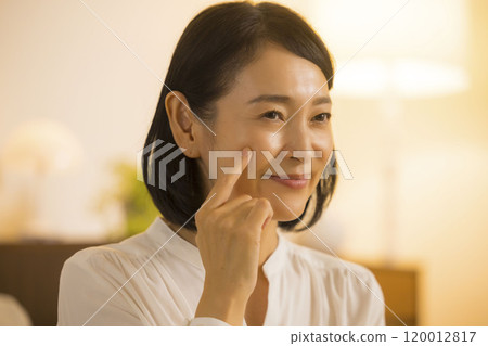 A middle-aged woman doing her skin care at night A middle-aged woman doing her skin care at night 120012817