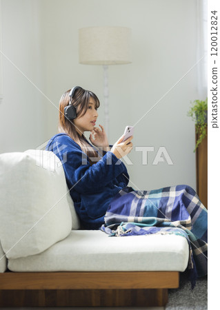 Woman in living room in winter with headphones 120012824