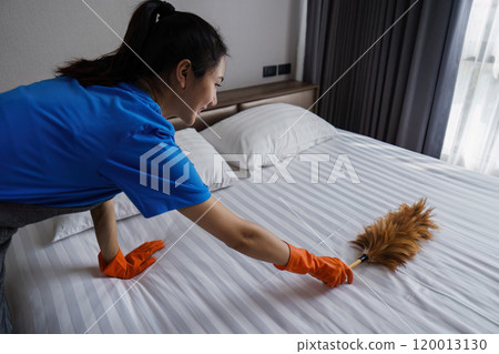 cleaning service woman cleaning dust on bed with feather duster. housekeeping cleaning service concept 120013130