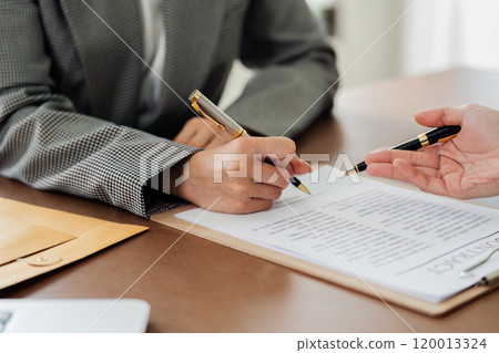 A woman is signing a document with a pen A woman is signing a document with a pen 120013324