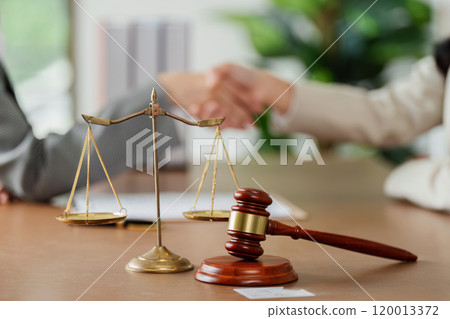 law and justice is represented by a mallet gavel of the judge, scales of justice, lawyer and client shaking hands 120013372