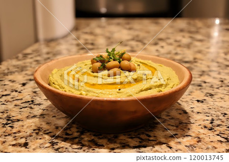 Creamy hummus with olive oil, paprika, and chickpeas in a rustic bowl on a warm kitchen countertop 120013745