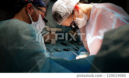 Two surgeons in surgical masks and scrubs are conducting a surgery with sterile surgical instruments in an operating room Two surgeons in surgical masks and scrubs are conducting a surgery with sterile surgical instruments in an operating room 120014060