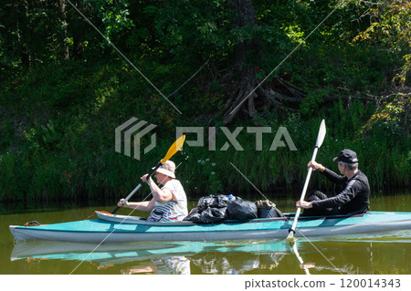 Family kayak trip for seigneur and senora. An elderly married couple rowing a boat on the river, a water hike, a summer adventure. Age-related sports, mental youth and health, tourism, active old age 120014343