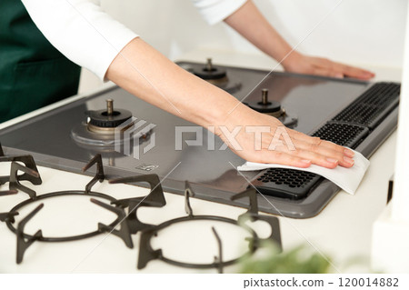 The hands of a middle-aged to senior woman wiping down a gas stove The hands of a middle-aged to senior woman wiping down a gas stove 120014882