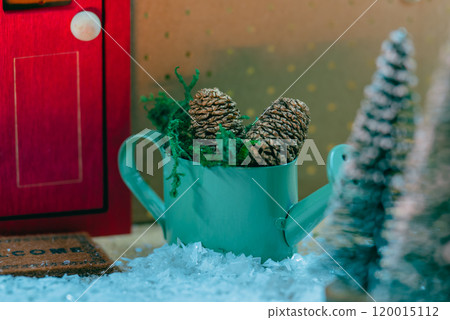 Winter scene decorated with pine cones and a green watering can Winter scene decorated with pine cones and a green watering can 120015112