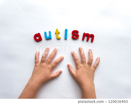 Childs hands and colorful letters spelling autism on white background 120016403