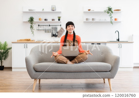 Caucasian woman meditating in lotus pose while working remotely on laptop 120016760