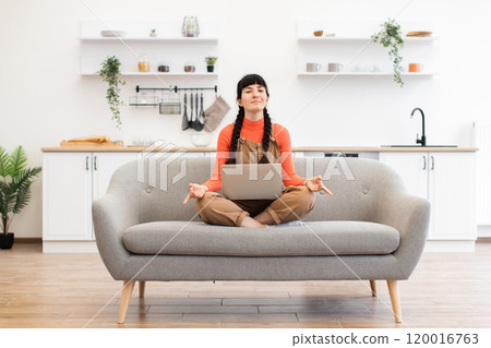 Caucasian woman meditating during remote work break at home office 120016763