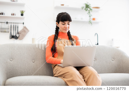 Caucasian woman working from home on laptop sitting on sofa 120016770