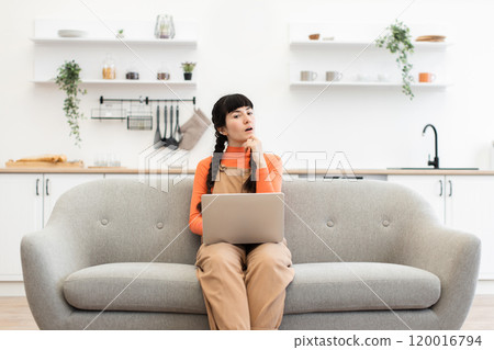 Caucasian woman working remotely from home on comfortable sofa with laptop 120016794