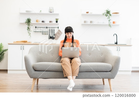 Young woman working on laptop in modern minimalist living room Young woman working on laptop in modern minimalist living room 120016800