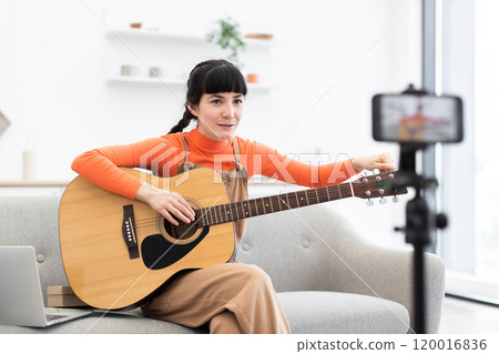 Caucasian female blogger recording guitar lesson at home studio setting Caucasian female blogger recording guitar lesson at home studio setting 120016836