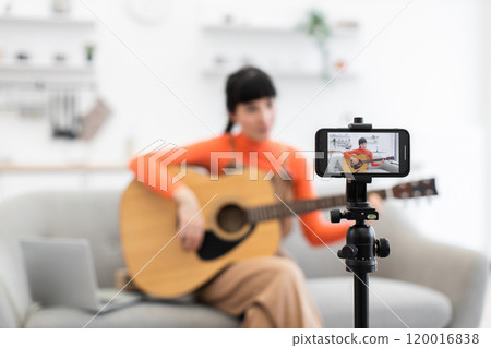 Caucasian woman teaching guitar in online video tutorial at home Caucasian woman teaching guitar in online video tutorial at home 120016838