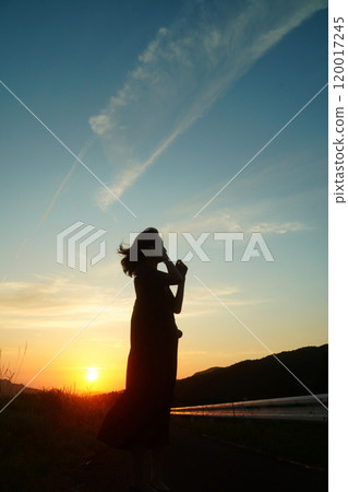 A woman looking up at the sunset 120017245