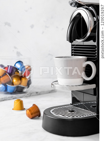 Coffee machine with espresso cup and coffee capsules pods in light morning kitchen background. Coffee machine with espresso cup and coffee capsules pods in light morning kitchen background. 120019267