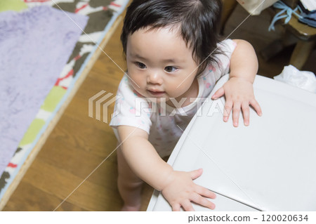 [Baby with twin tails standing up by holding on to a trash can] 120020634
