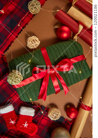 A green wool scarf tied with a red ribbon is placed in the center of the photo with Noel decorations located around it. Perfect composition for a vertical Christmas photo with a viewpoint angle. A green wool scarf tied with a red ribbon is placed in the center of the photo with Noel decorations located around it. Perfect composition for a vertical Christmas photo with a viewpoint angle. 120021186