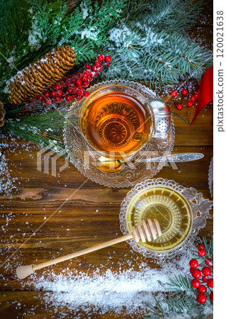 Christmas background, cup of tea with honey and croissant, branch of a Christmas tree in the snow 120021638
