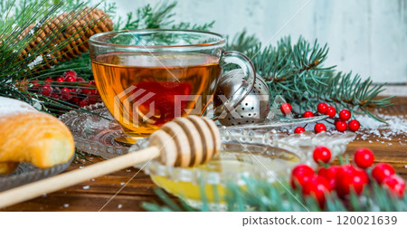 Christmas tea in glass Cup . composition with cookie, pine branches, cones on background of garlands on wooden table 120021639