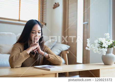 Young adult woman pondering and checking work schedule plan on notebook Young adult woman pondering and checking work schedule plan on notebook 120023372