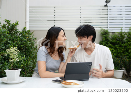 Loving asian couple sharing a breakfast and enjoying relaxed outdoor together 120023390