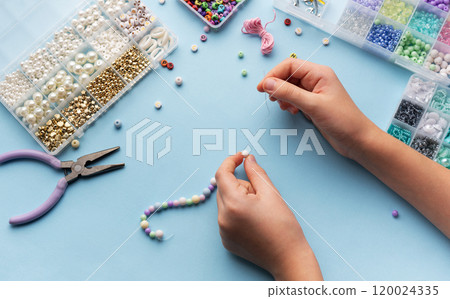Creating colorful beaded jewelry with vibrant materials on a crafting table Creating colorful beaded jewelry with vibrant materials on a crafting table 120024335
