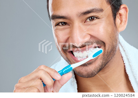 Brushing teeth, grooming and portrait of Asian man in studio on gray background for wellness. Toothbrush, toothpaste and smile with face of happy person in bathroom for dental hygiene or oral care 120024584