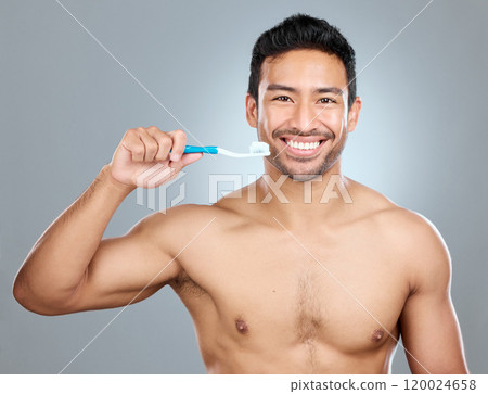 Brushing teeth, portrait and smile of shirtless man in studio on gray background for cosmetic wellness. Dental hygiene, oral care and toothbrush with happy person in bathroom for cleaning routine 120024658